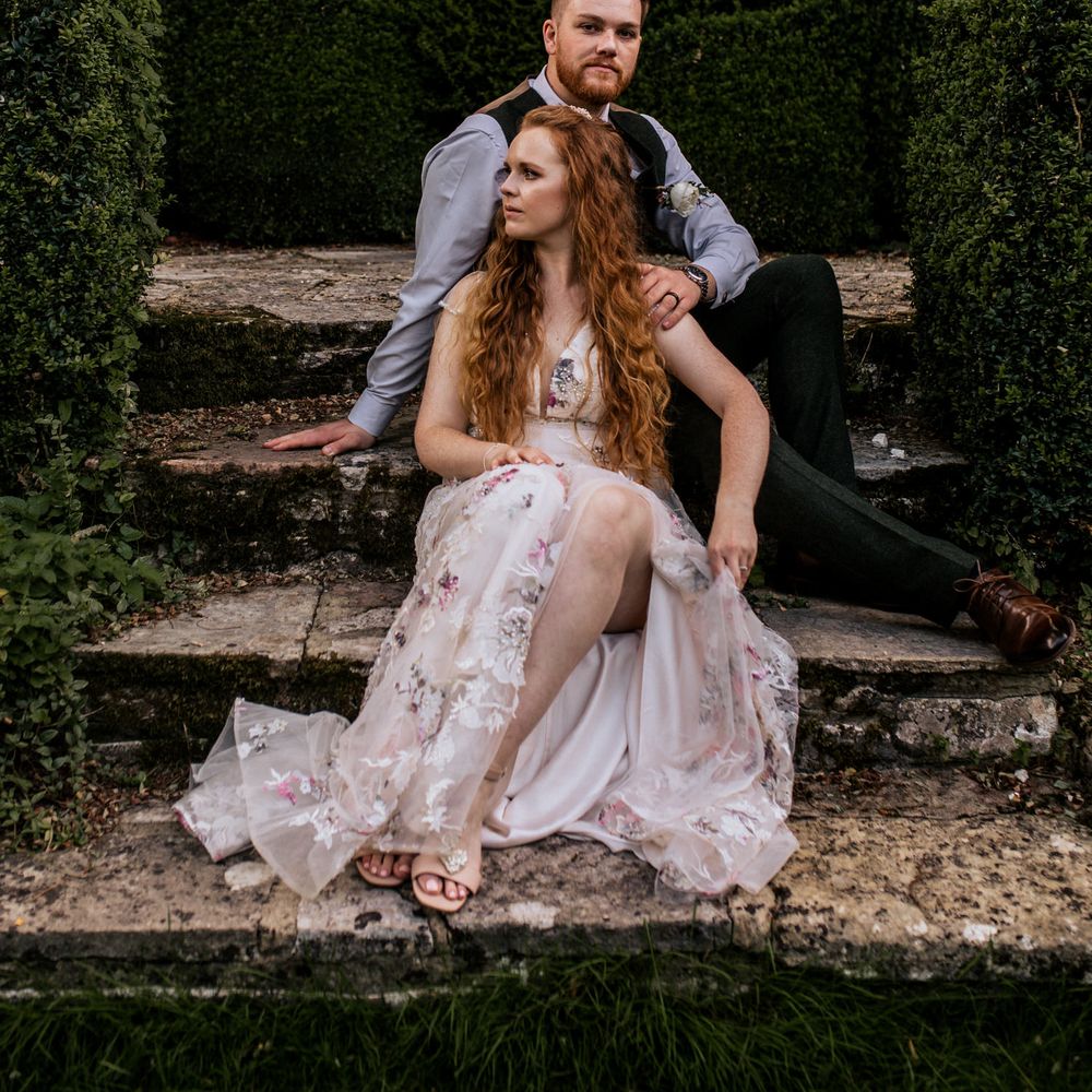 Bride & groom pose outside with bride wearing appliqué wedding dress