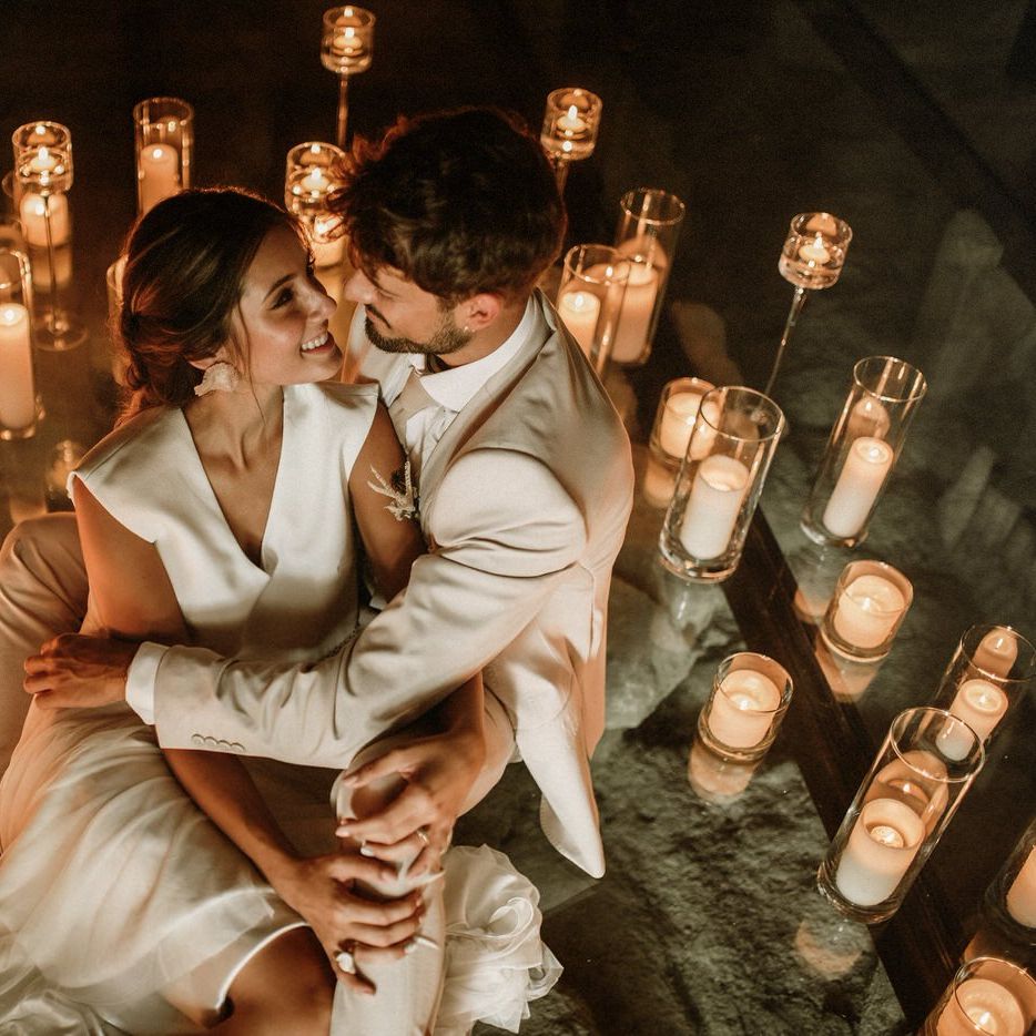 Bride and groom portrait surrounded by lots of pillar candles in glass holders 