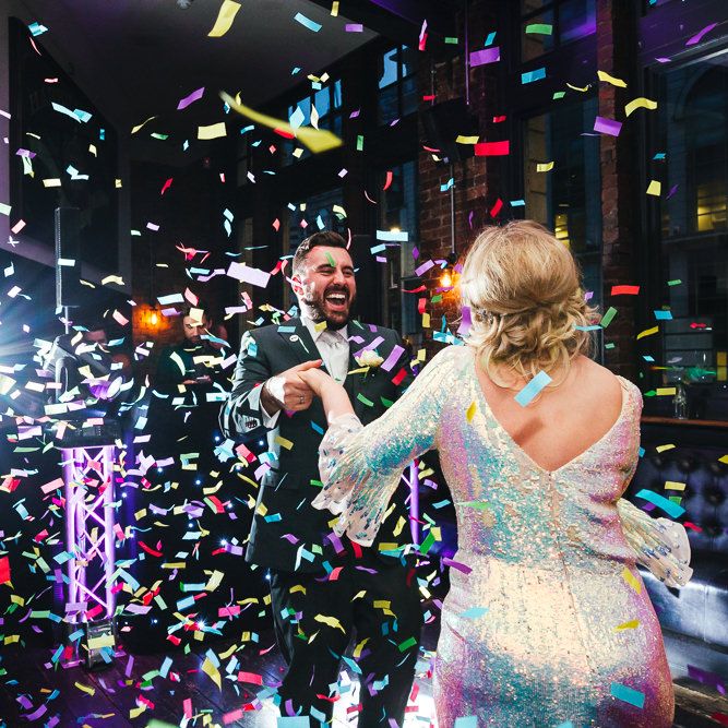 Bride & groom dance together whilst confetti blows around them