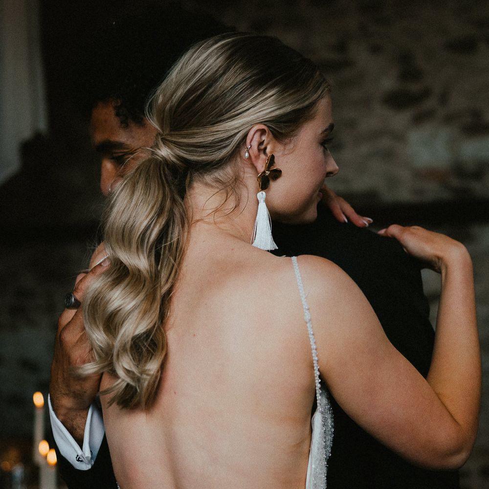 Bride with a wavy ponytail and floral and tassel earrings 