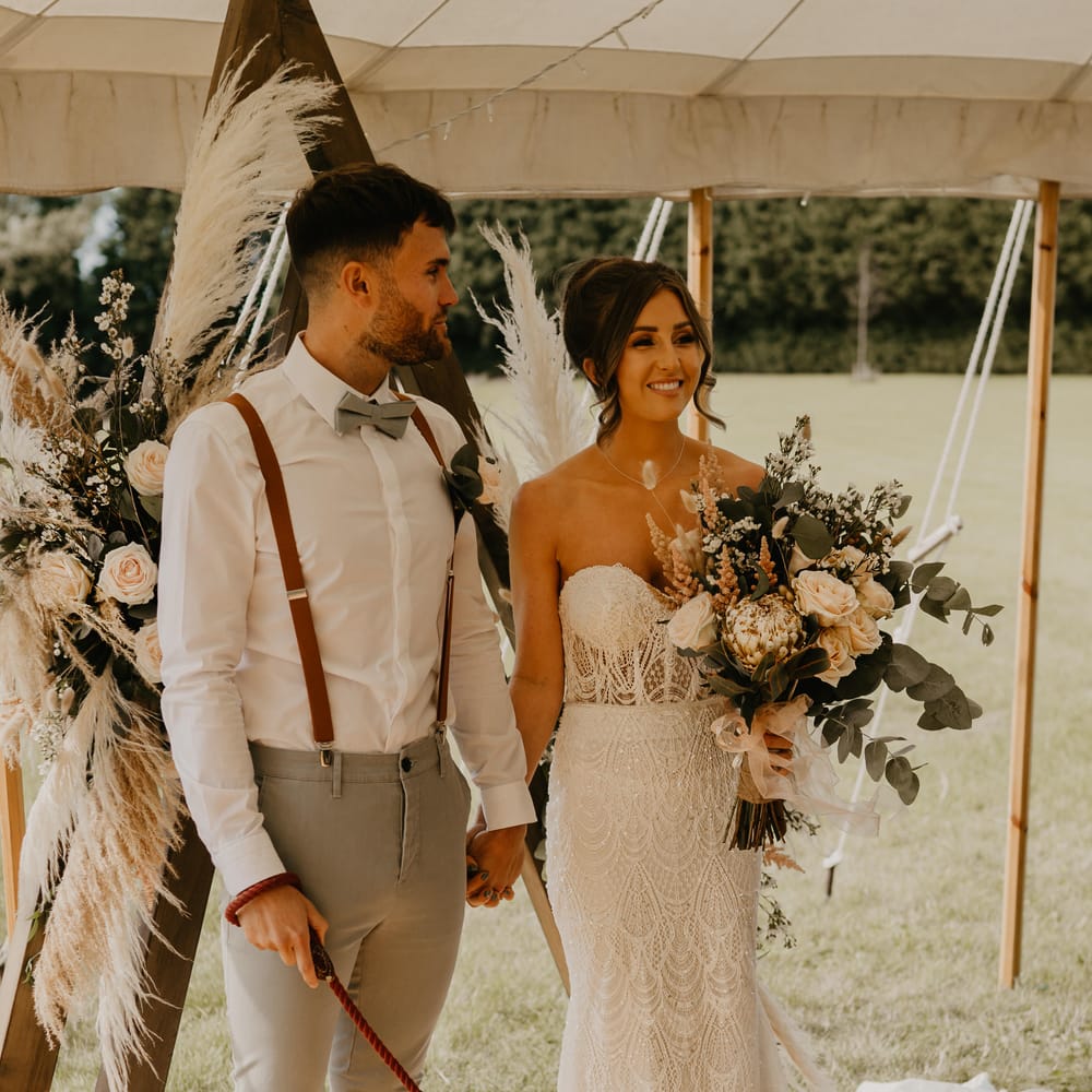 Bride & groom hold their dog on their wedding day whilst stood inside marquee | Mark Bamforth Photography