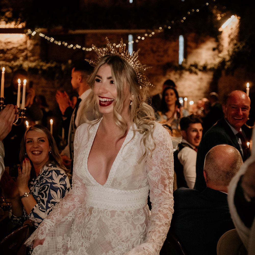 Stylish bride in a lace wedding dress with plunging neckline and gold crown 