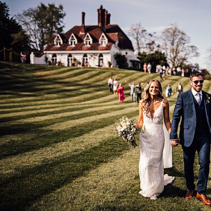 Bride and groom wearing sunglasses walk over to their reception 