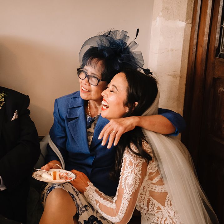 Bride gets a hug from her mother as they laugh and smile together and eat some cake 