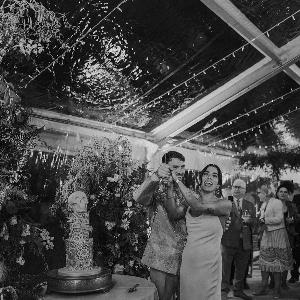 Bride and groom cutting their skull wedding cake with Indian paisley pattern
