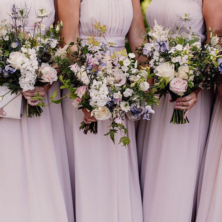 Purple, pink and white flower wedding bouquets held by bridesmaids in blush pink chiffon dresses