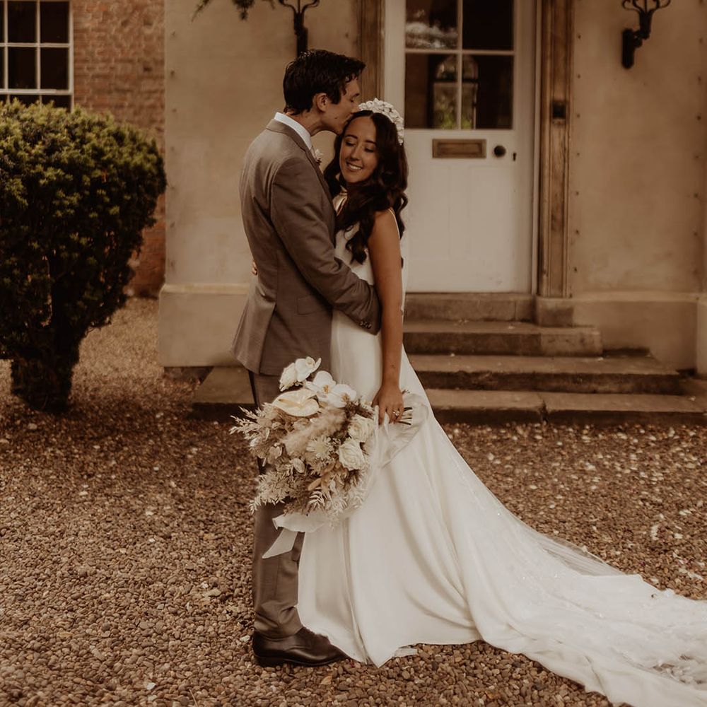 Groom kisses the bride on the forehead as they take their couple portraits together