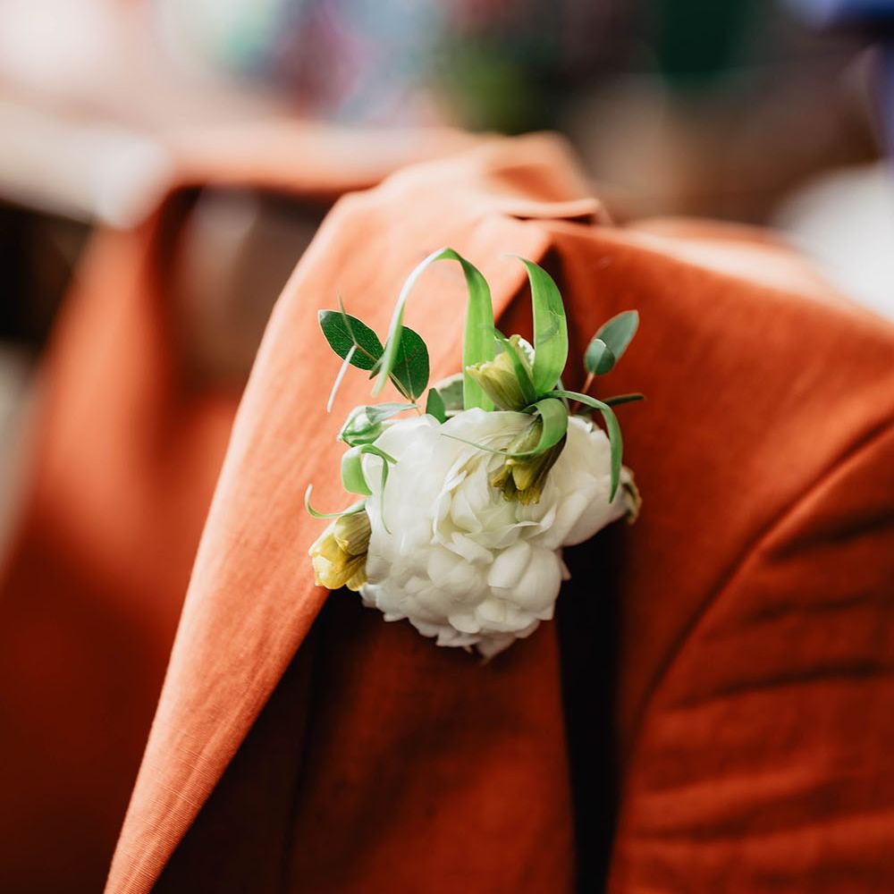 Groom wears orange Paul Smith suit complete with white floral buttonhole 