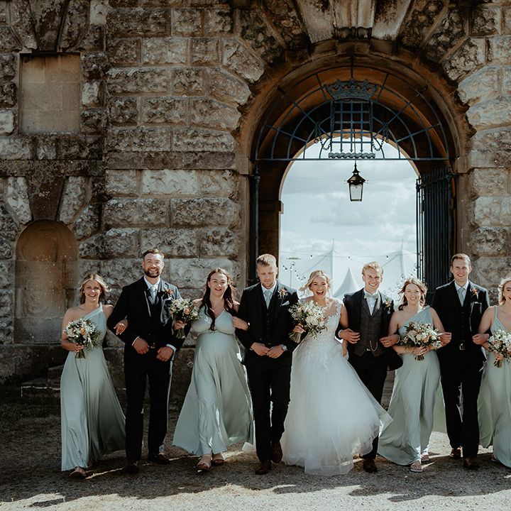 Bridesmaids in sage green dresses with groomsmen in sage green bow ties with the bride in a princess wedding dress