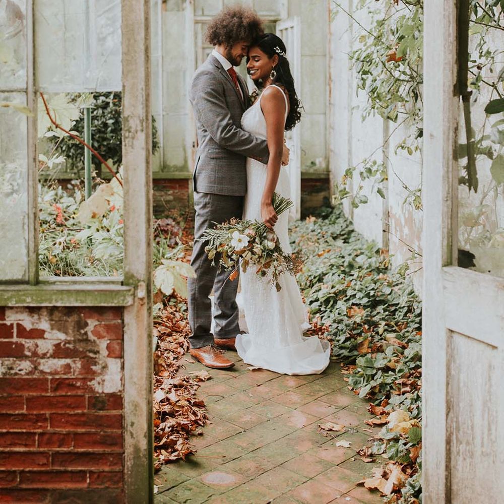 Bride and groom embracing in green house type room at Hooton Pagnell Hall