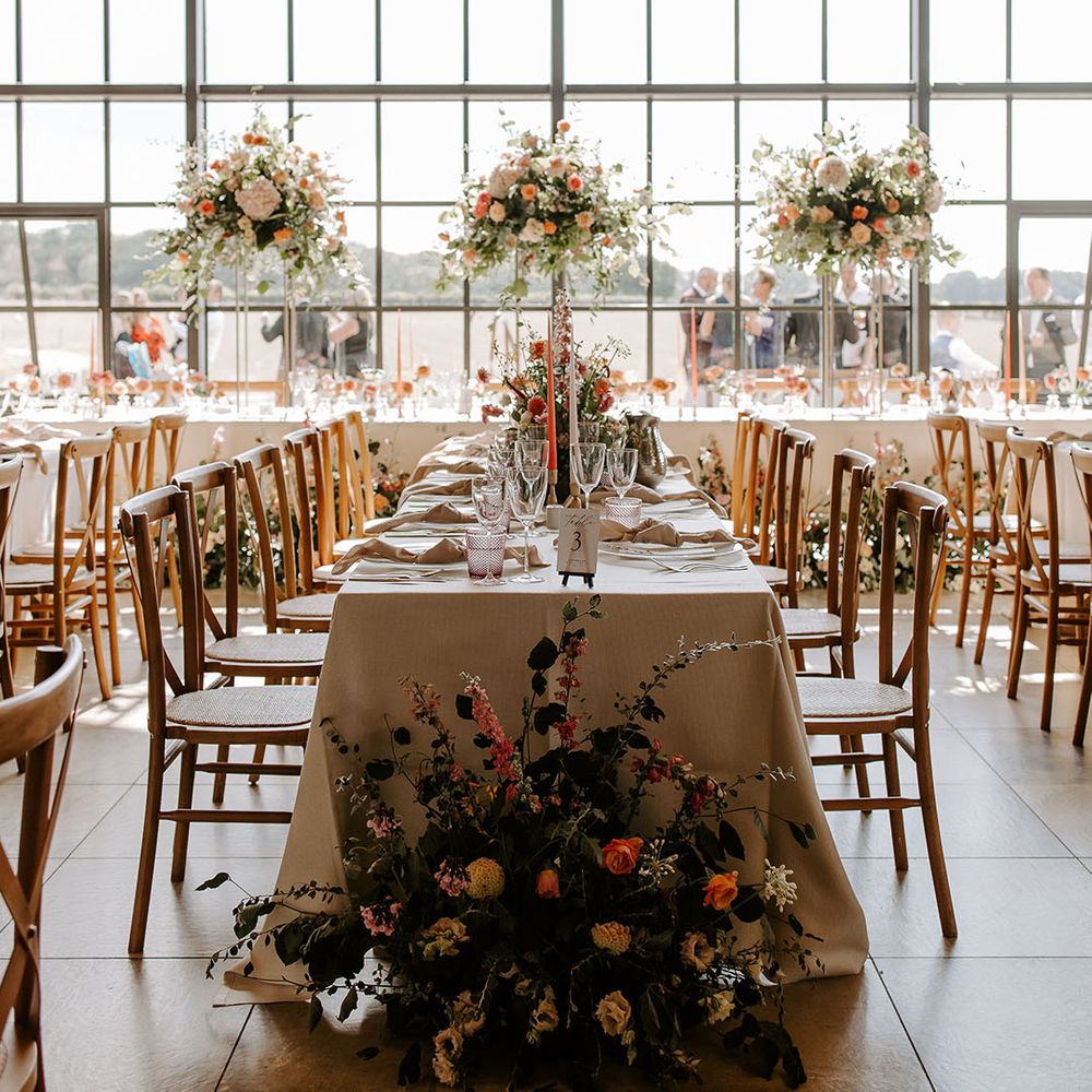 Botley Hill Barn wedding reception complete with striking floral installations to top table with pops of orange and green foliage