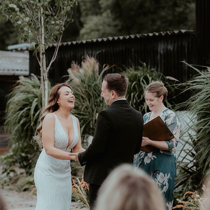 Bride in sequin Made With Love wedding dress smiling as she stands at the altar with the groom for their outdoor humanist and handfasting ceremony 