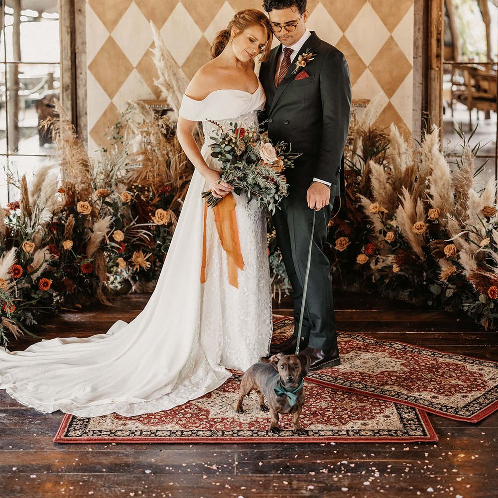 Bride in Love Spell wedding dress holds Autumnal wedding bouquet tied with orange raw edge ribbon