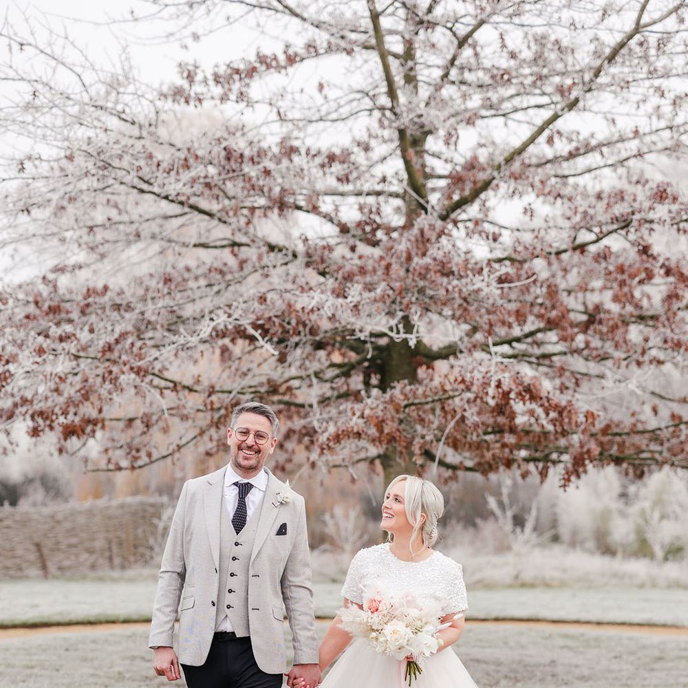 Groom in light grey suit jacket walking with the bride in a beaded short sleeve top and tulle bridal skirt