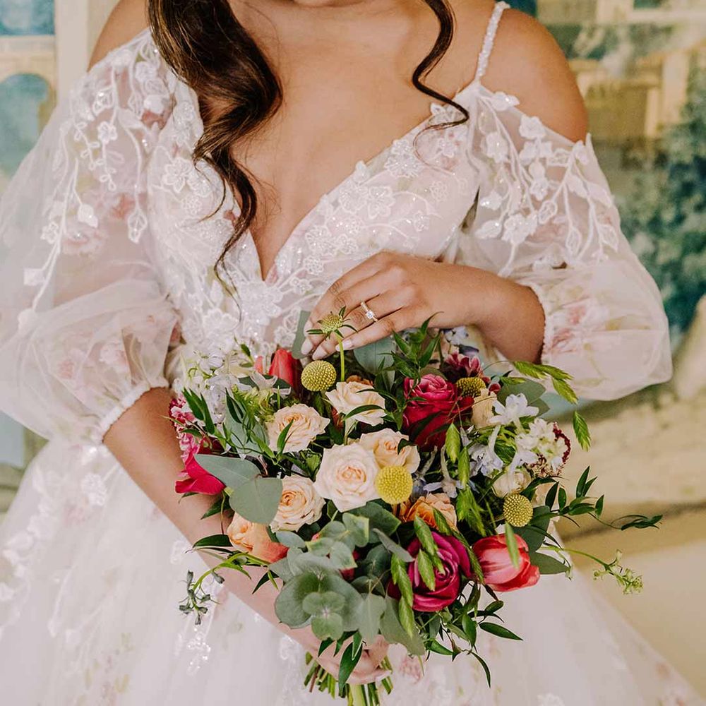 Bride in v-neck long sleeve shoulder cut out 3d appliqué wedding dress with flecks of gold holding large dried flower, eucalyptus, spring florals and garden rose bridal bouquet 