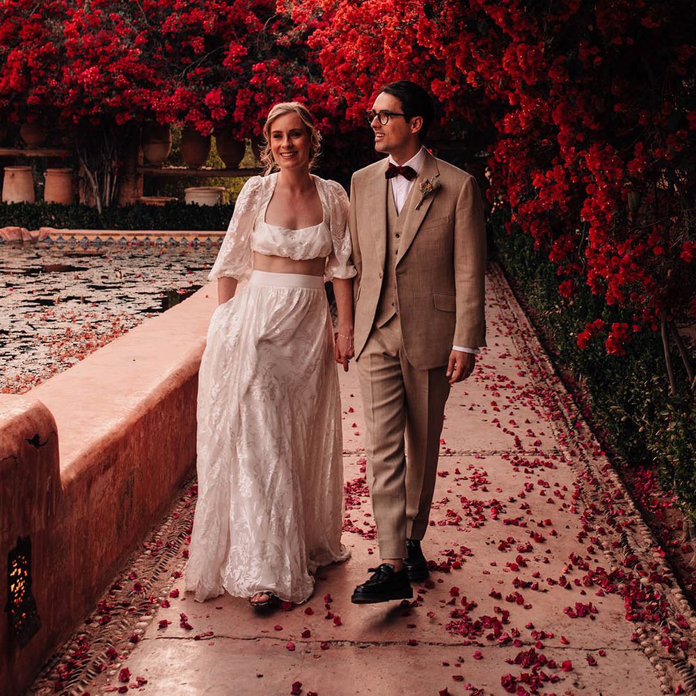 Bride and groom walking amongst red flowers in Marrakech for destination wedding 