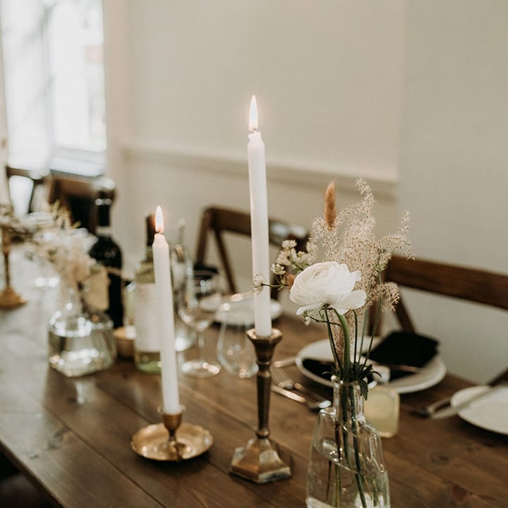 Simple and minimal wedding table decorations with bud vases full of white flowers and taper candles 