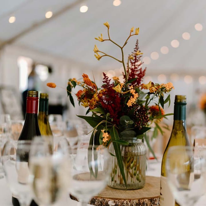 Dried orange and yellow flower and foliage wedding centrepieces on wooden tree trump circles at Broadfield Court