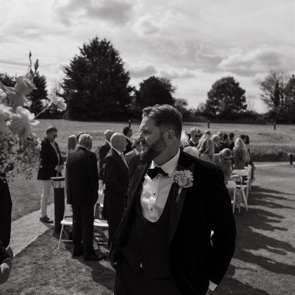 Groom in black tuxedo at outdoor wedding waiting for the bride 