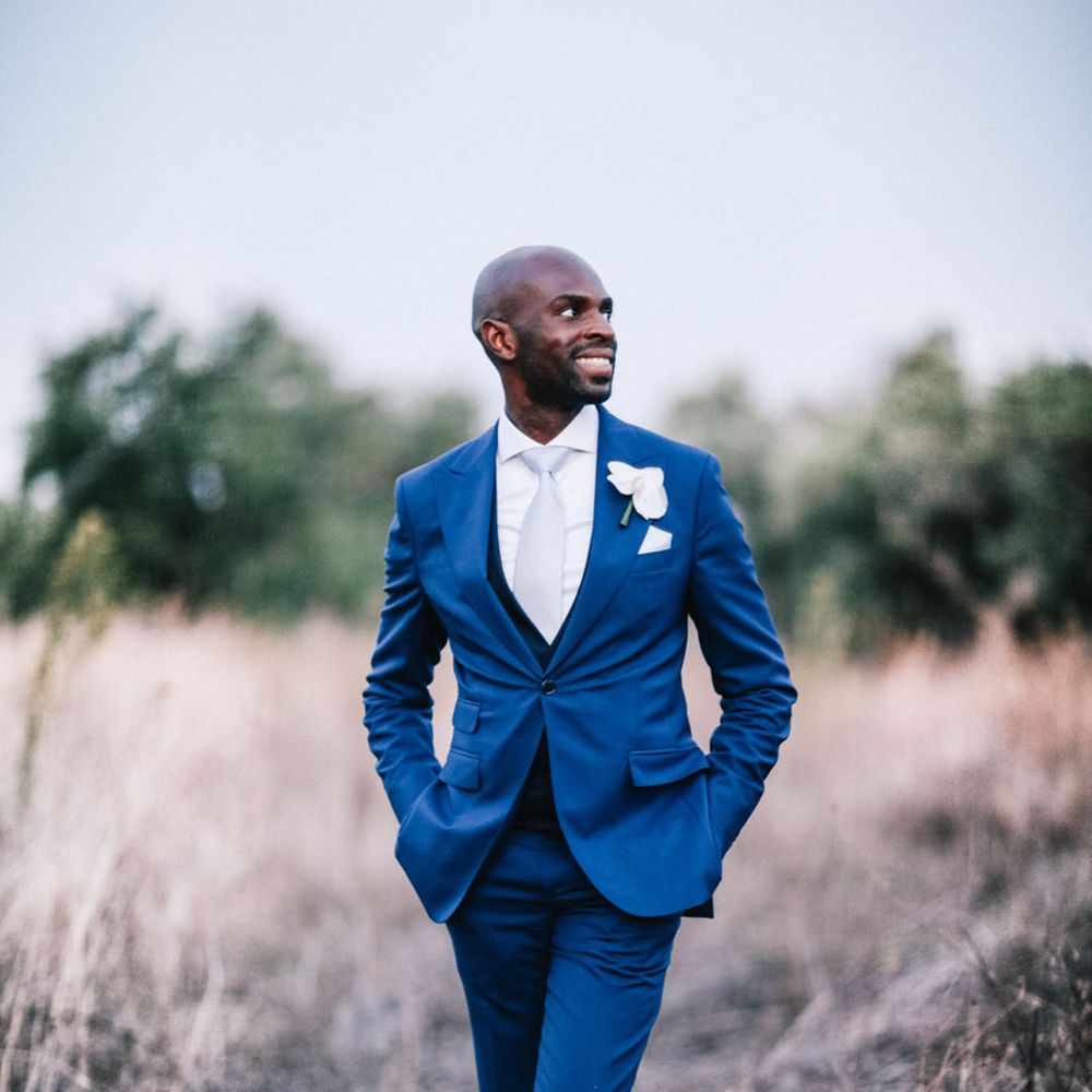 Dark blue groom suit with white shirt, white tie and white orchid buttonhole 