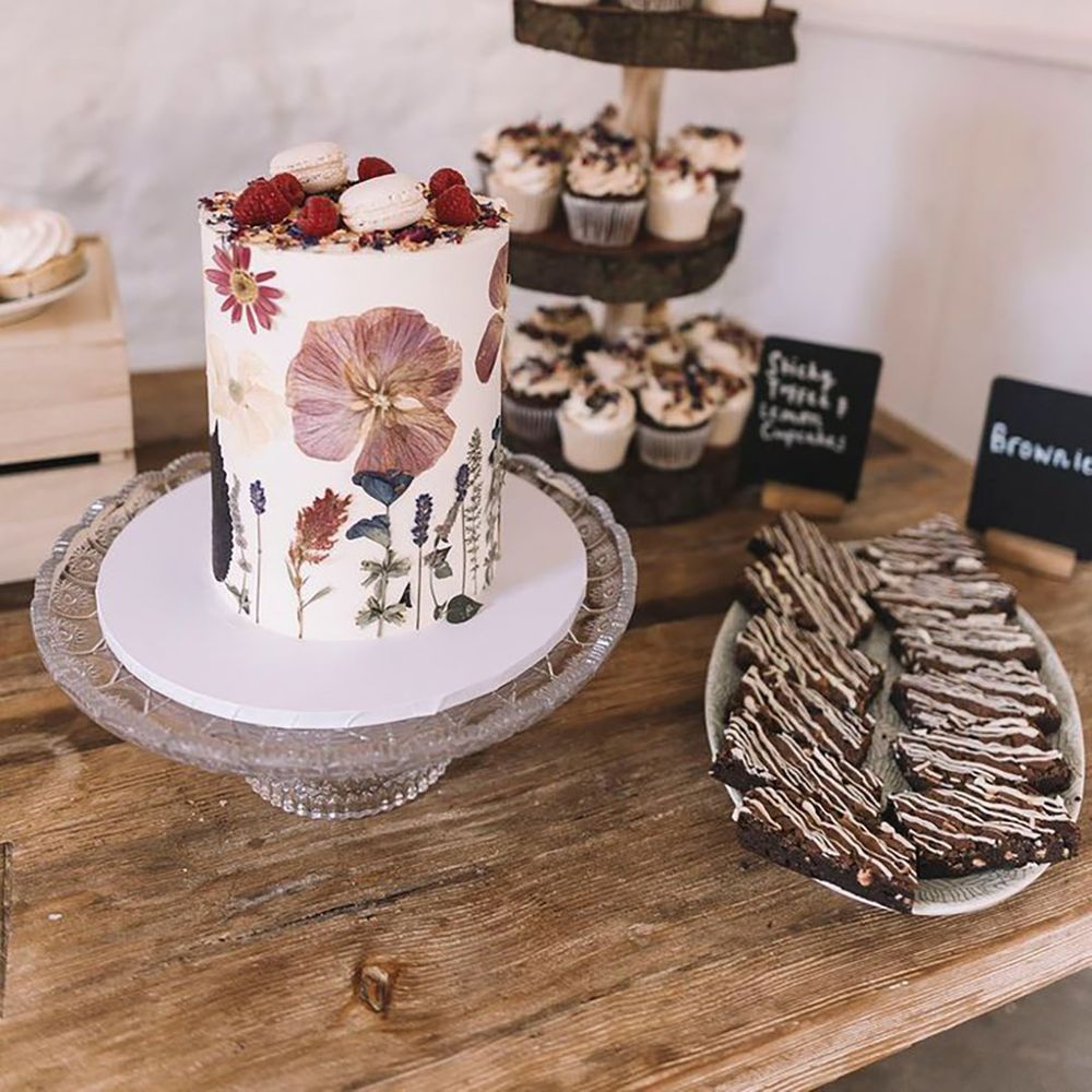 Wildflower pressed wedding cake on a wooden dessert table with brownies and cupcakes 