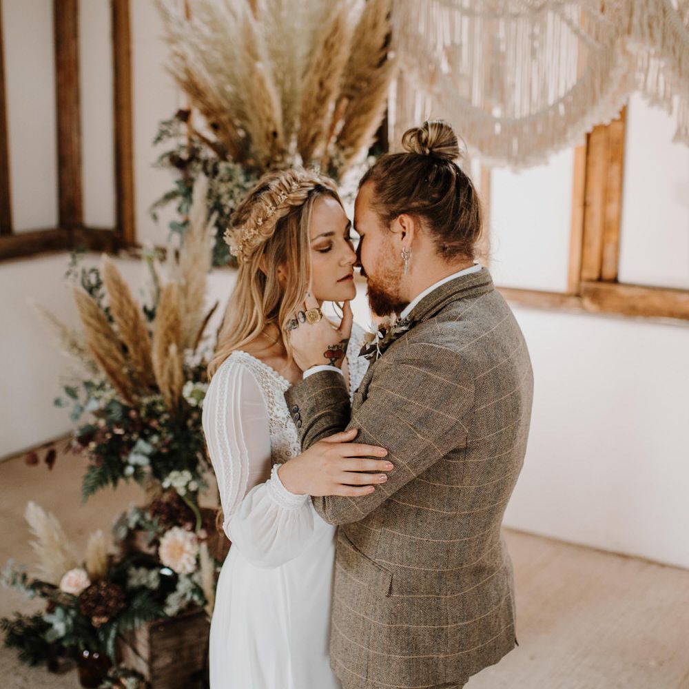 Bride and groom kissing at boho luxe wedding with pampas grass and macrame backdrop 