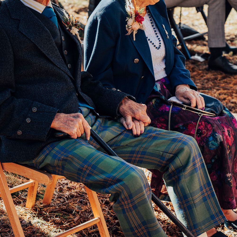 Wedding guests hold hands during woodland wedding ceremony