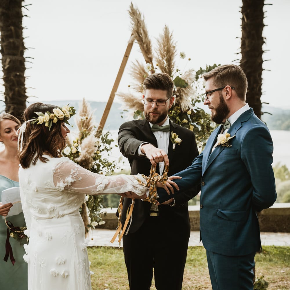 Bride and groom holding their arms out for the handfasting ceremony 