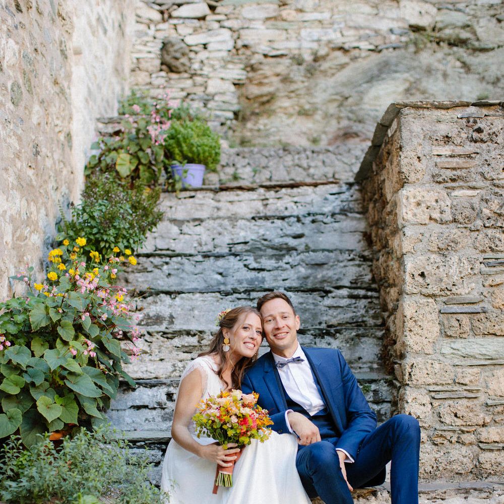 The bride and groom sitting on steps at Valeni Boutique Hotel in Greece