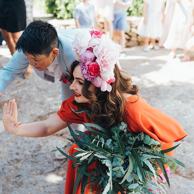 Brides bend down to high five children on their wedding day outside in Menorca