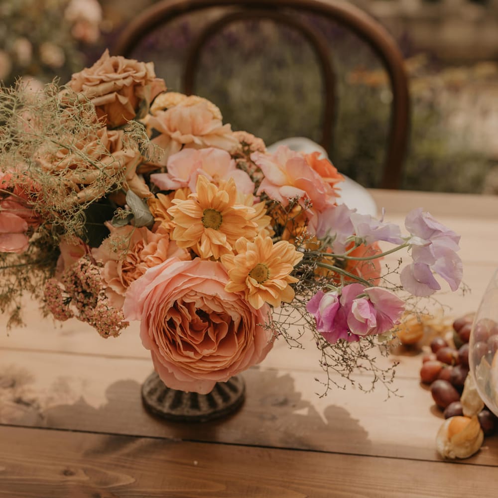 centrepiece flowers in a vessel with pastel orange, peach, coral and pink wedding flowers 