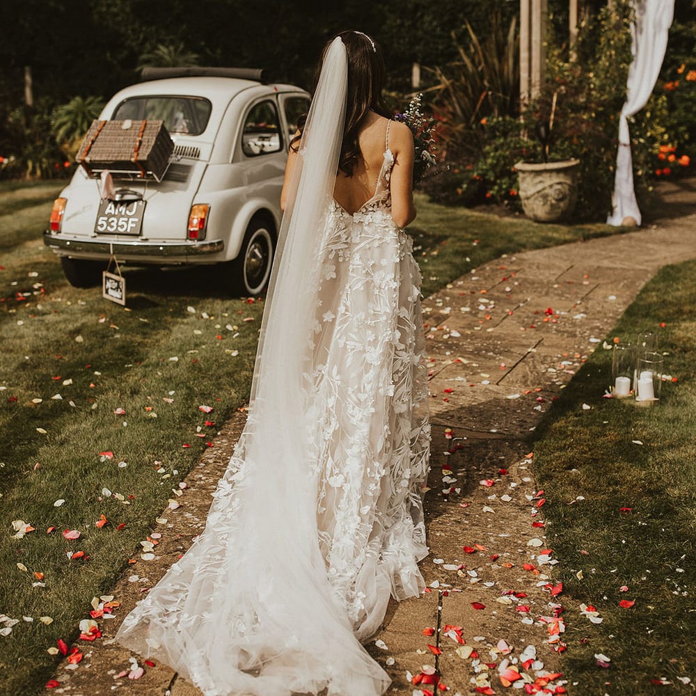 Bride walks down pathway covered in colourful confetti on her wedding day