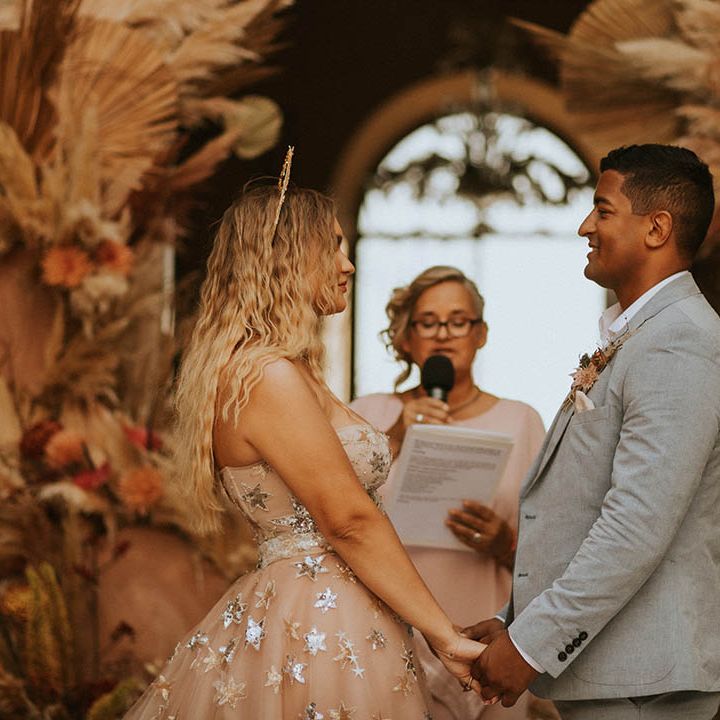 Bride & groom hold hands and look lovingly at one another on wedding day