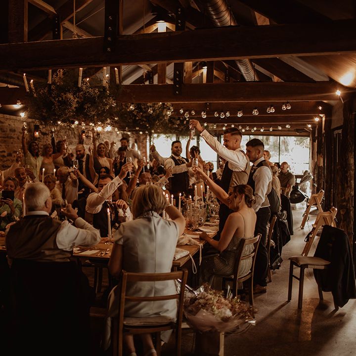 Rustic wedding at Dewsall Court with wedding guests raising their glasses during the wedding reception speeches 