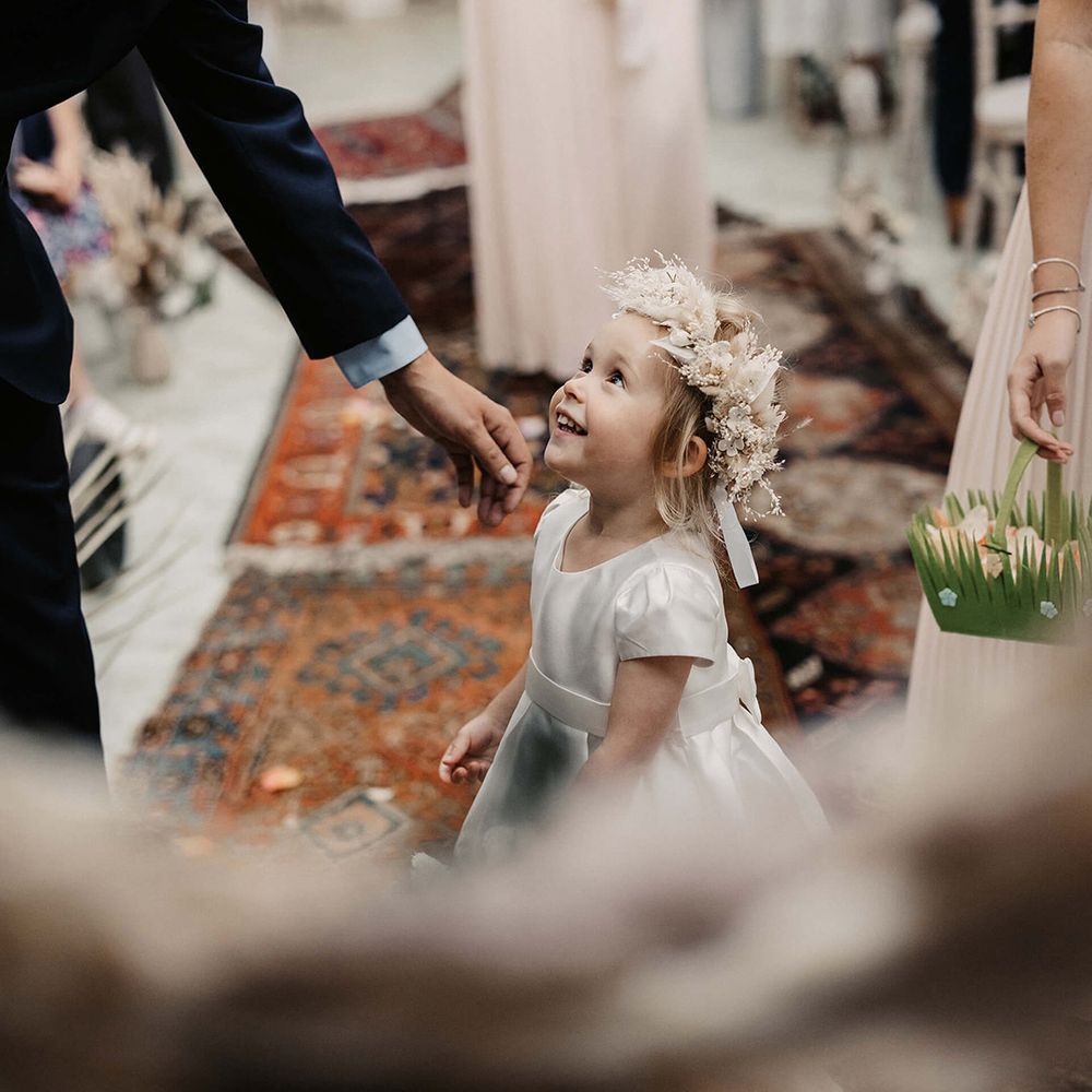 Flower girl wears white dress complete with neutral toned dried floral crown