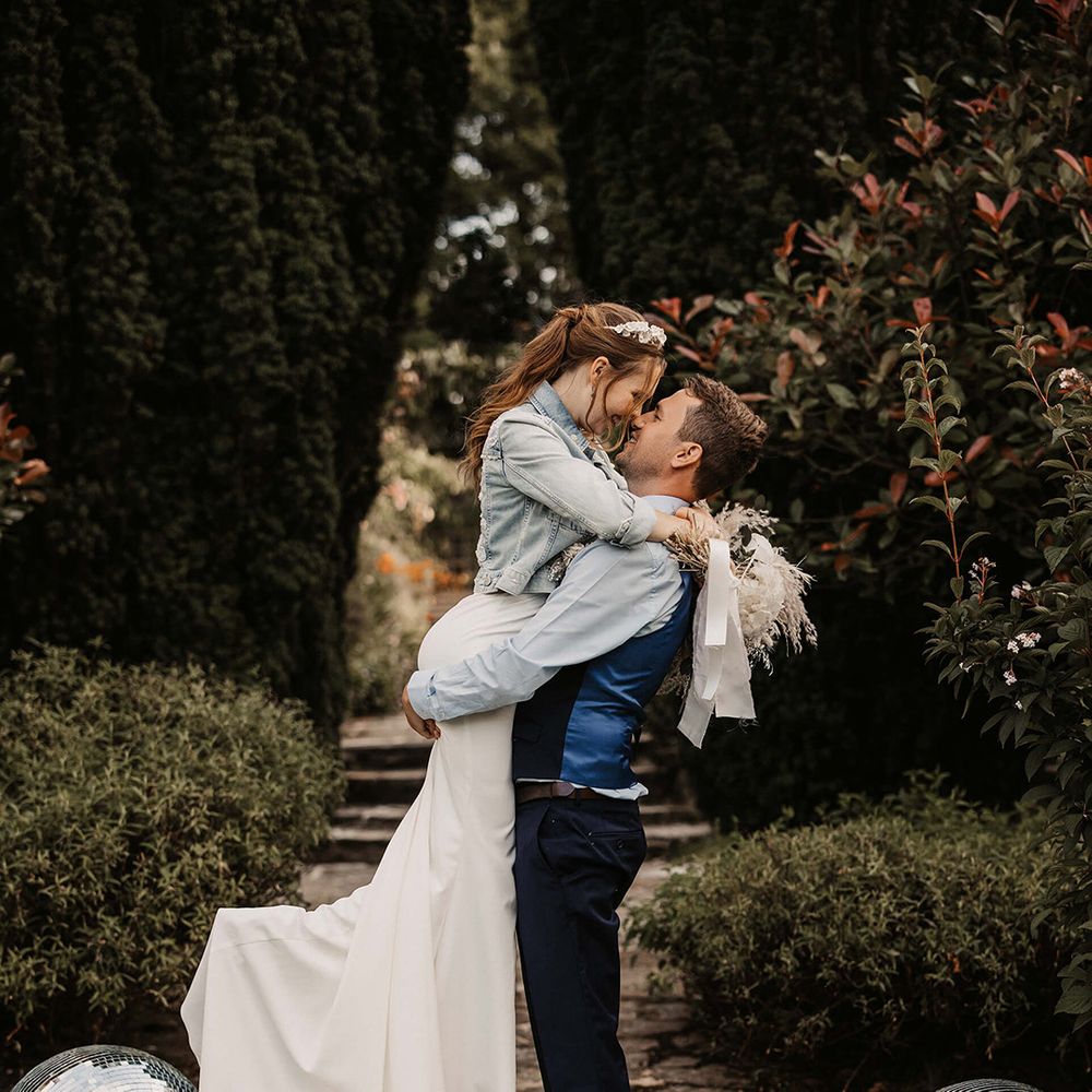 Groom lifts his bride outdoors on their wedding day