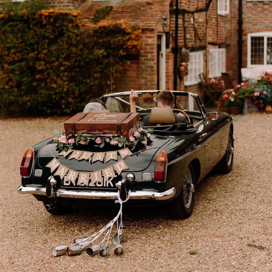 Vintage wedding car with bunting and can decor