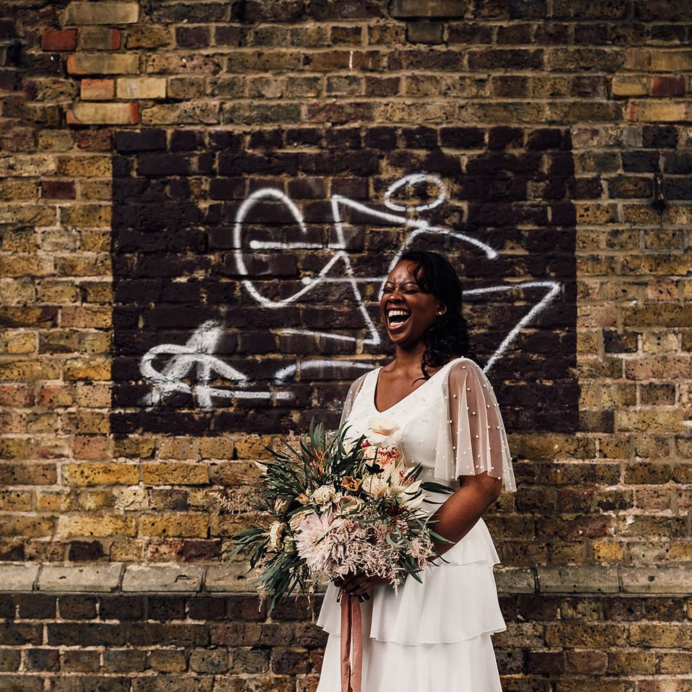 Beautiful Black bride in a layered skirt and pearl top by Story Of My Dress holding a dried and fresh flower wedding bouquet 