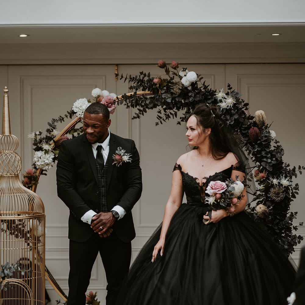 Bride & groom look lovingly at one another as groom wears three piece suit 