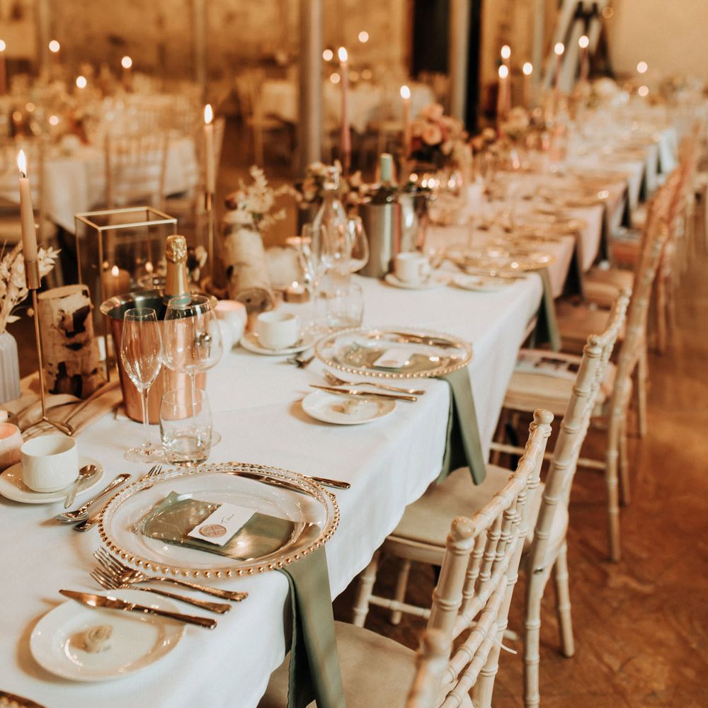 Long white wedding top table with clear plates, green napkins and pink dinner candles for wedding reception at Holmes Mill wedding venue