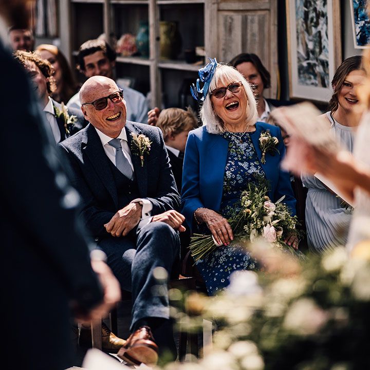 Mother and father of the bride laugh during the wedding vows being read 