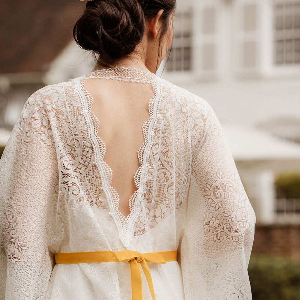 East Asian bride in a lace kimono style wedding dress red with yellow ribbon with chic bridal up do decorated with fresh flowers 