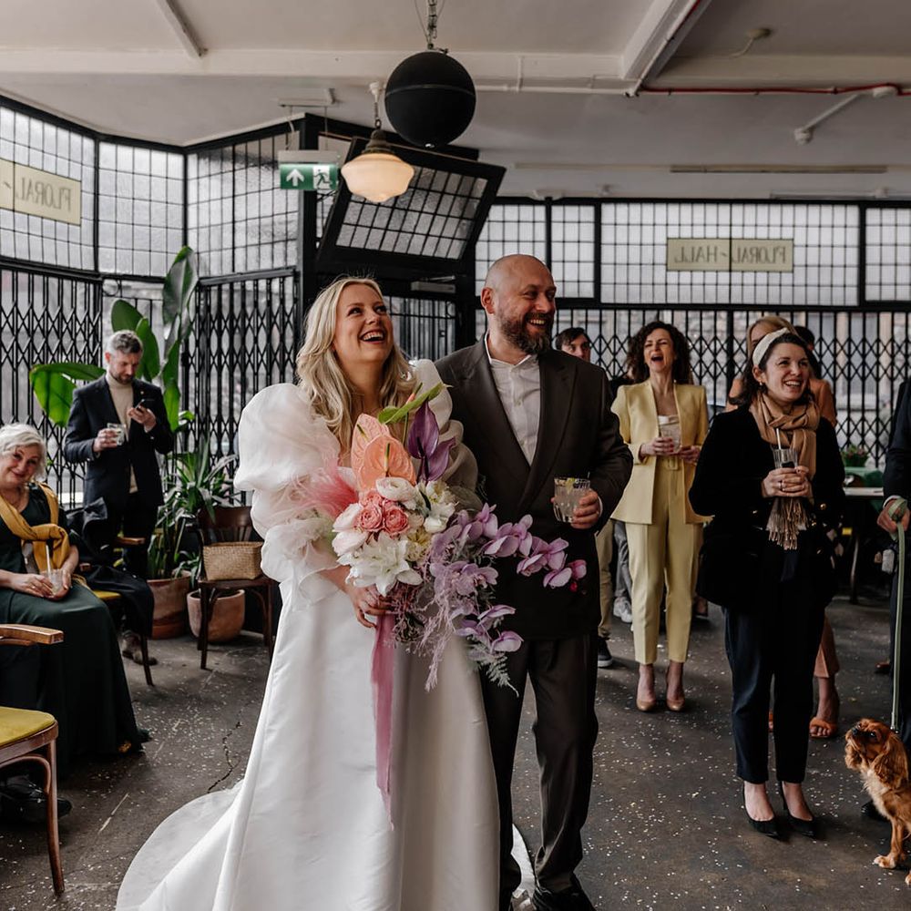 Drinks reception at Floral Hall with bride in a puff sleeve wedding dress holding a pastel wedding bouquet with orchids 