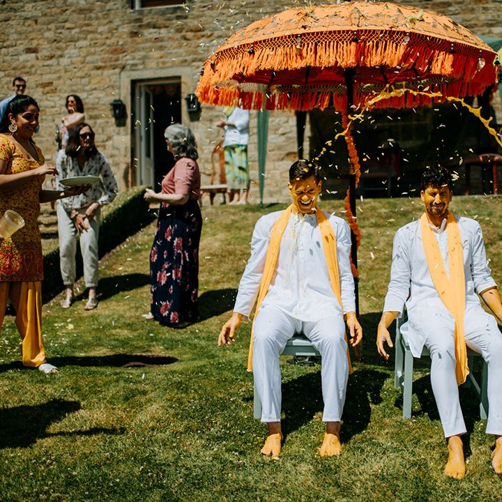 Grooms wear matching outfits and have their faces covered in Haldi paste during outdoor ceremony