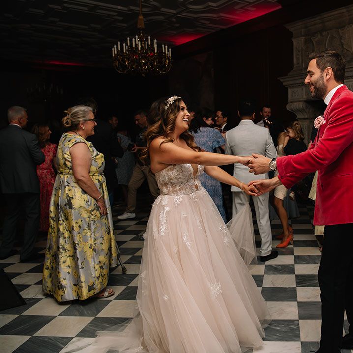 The bride and groom participate in their first dance together as they stand on the marble checkerboard dance floor