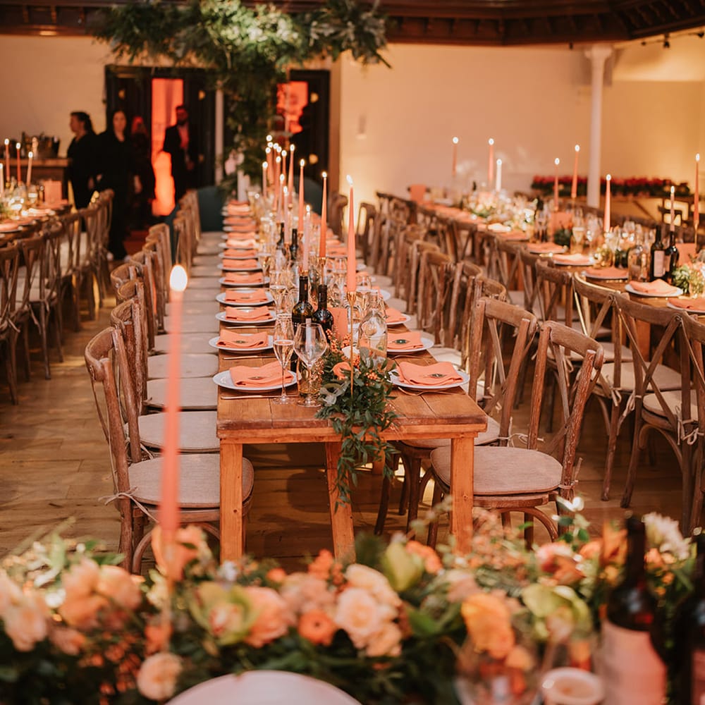 Silver and gold wedding streamer decorations, orange tapered candles, orange napkins, orange rose and foliage tablerunners and fairy lights 