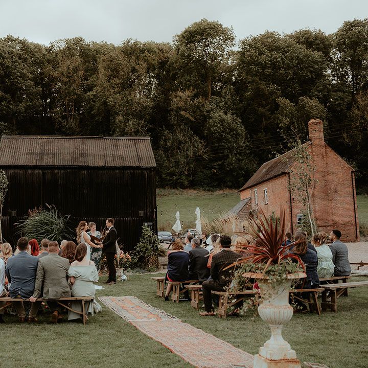 Rhyse Farm wedding venue with the bride and groom standing for an outdoor wedding ceremony. on a cloudy day 