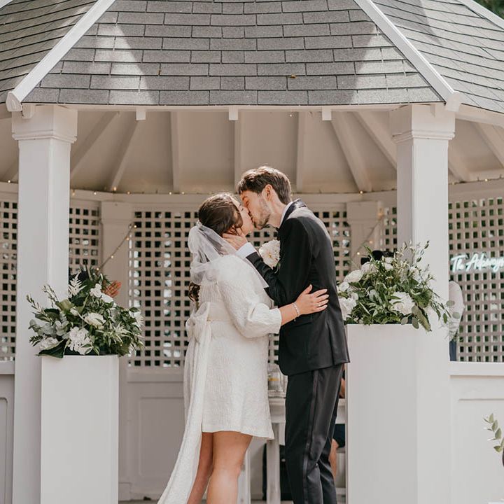 The bride and groom share their first kiss as a married couple at their outdoor wedding ceremony 