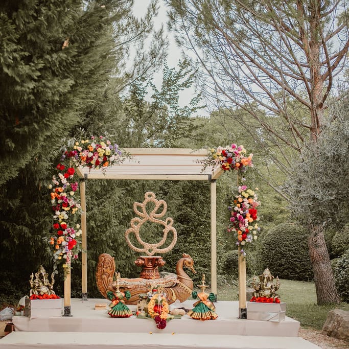 outdoor Hindu marriage ceremony with mandal decorated with colourful flowers 