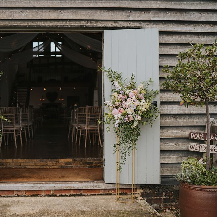 Pastel pink and lilac wedding flowers decorating the entrance to Dove Barn wedding venue 